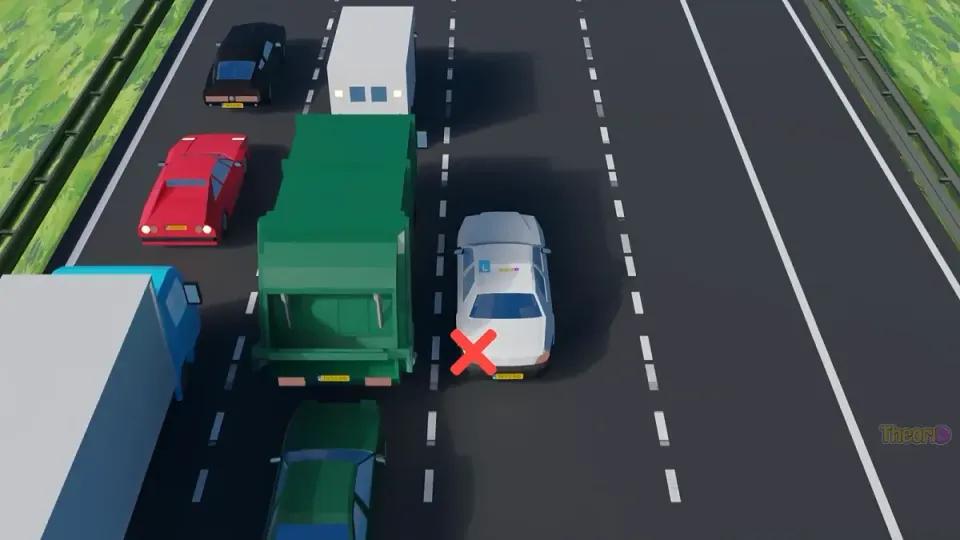 Learner car in busy traffic next to a lorry, with a red cross at the left indicator